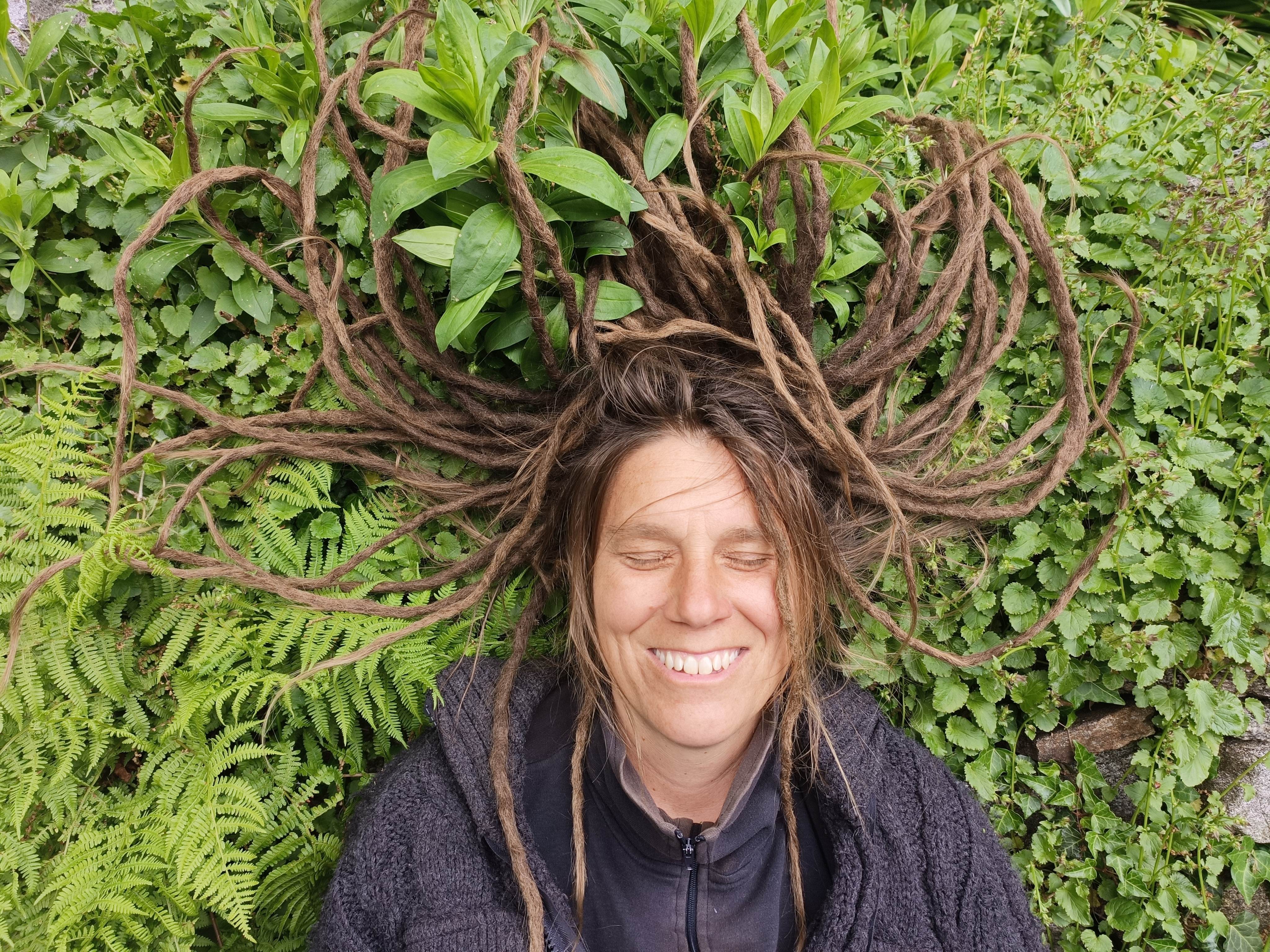 Sandra umgeben von Farn und Wildkräutern, mit ausgebreiteten Dreadlocks